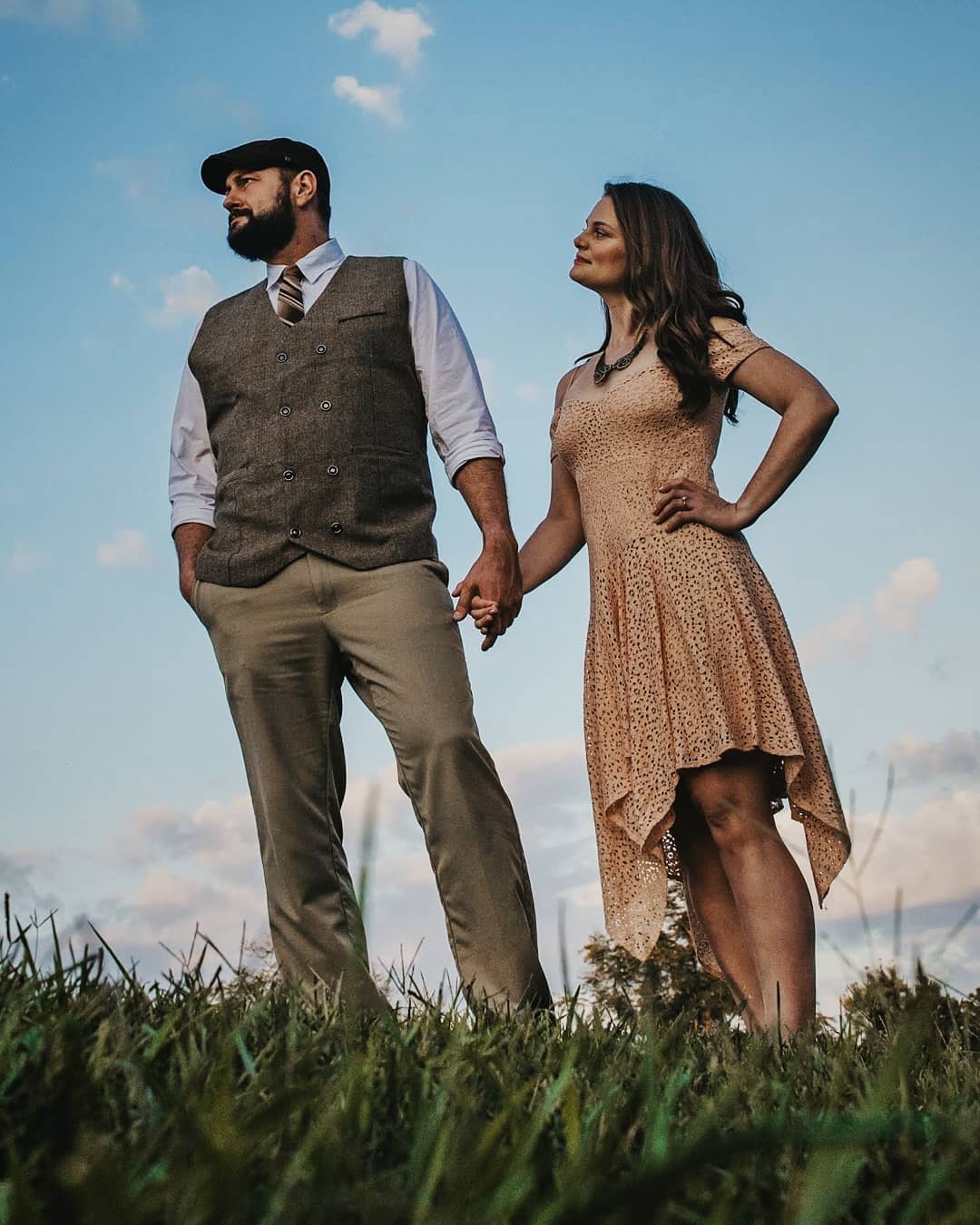 kat-andrew Andrew and Kat holding hands in a field under a blue sky.