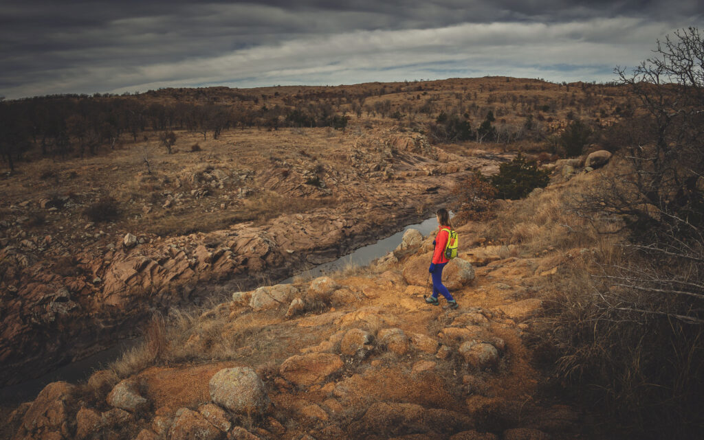Woman hiking in rocky terrain near West Cache Creek in Wichita Mountains Wildlife Refuge, Oklahoma.
