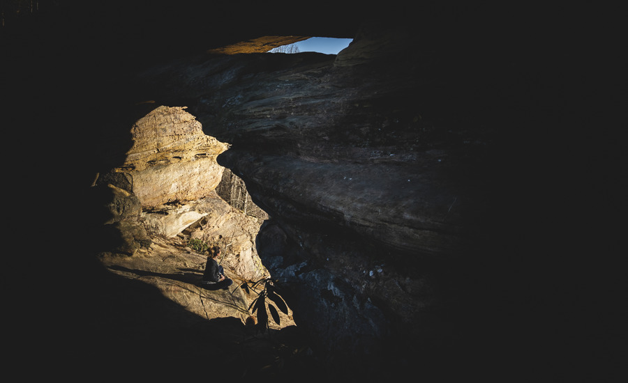 Woman hiker seated beneath Double Arch at Red River Gorge in Kentucky.